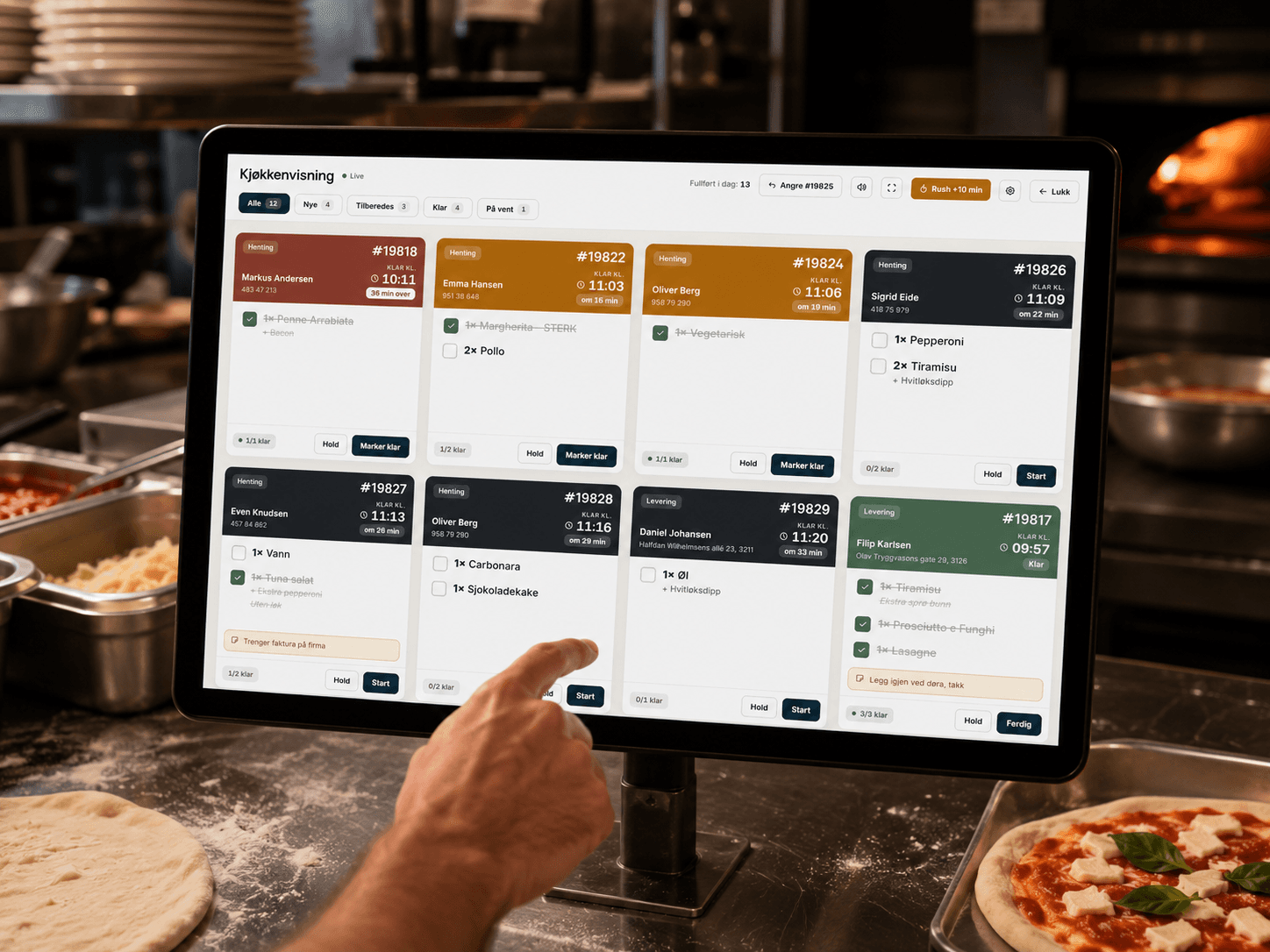LettBestilt kjøkkenskjerm (KDS) med aktive ordre, montert i et restaurantkjøkken